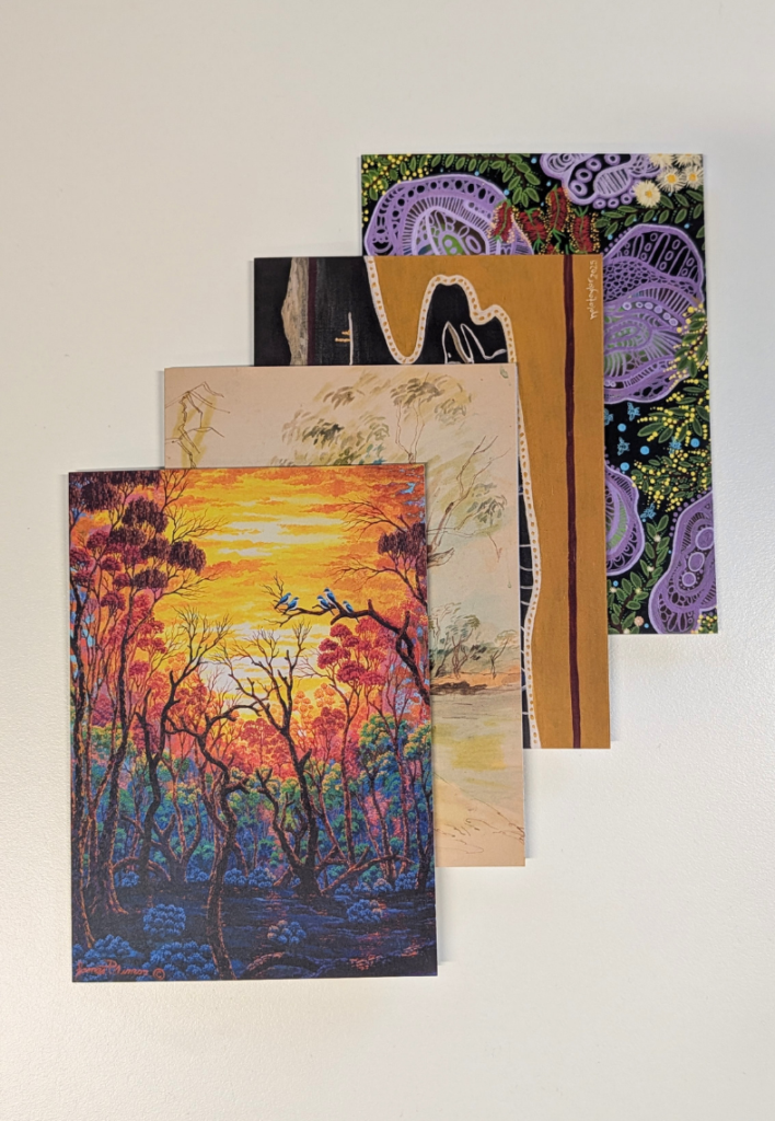 Stack of five art prints layered diagonally on a white surface, including a colorful sunset forest in the front and abstract patterns behind.